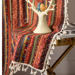 Detail of bohemian cotton linen runner with gold stripes and white tassels on a marble table