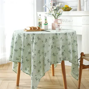Detail of light green floral round tablecloth with daisy embroidery and elegant drape