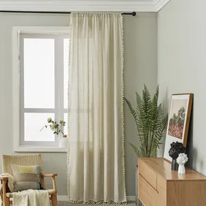 Close-up of beige linen curtains with tassel trim and rod pocket hanging detail