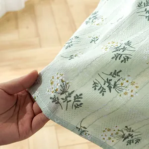 Close-up of light green floral tablecloth with 3D embroidery texture and striped linen fabric