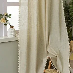 Detail of beige linen curtain with decorative fringe edge in a cozy Nordic style room