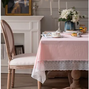 Detail van roze tafelkleed met witte delicate kantrand en een elegante draperende afwerking