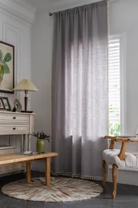 Detailed texture of gray linen stripe curtain with elegant cream tassel trim detail