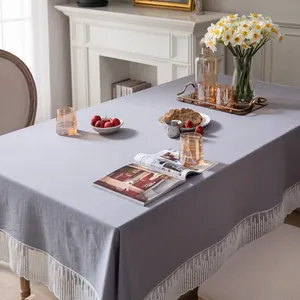Detailopname van grijs tafelkleed met witte kwastjesrand op een eettafel