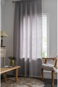Detail of lavender linen curtain with elegant off-white tassel trim for a cozy home feel