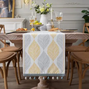 Dettaglio del runner da tavola moderno con foglie gialle e nappe di perline blu eleganti