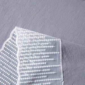 Detailopname van paarse getextureerde stof met elegant wit gebloemd kant aan de rand