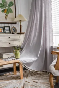 Detail of lilac linen curtain featuring white tassel fringe and natural woven texture