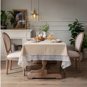 Detail van elegant beige tafelkleed met witte kanten rand op een houten tafelblad