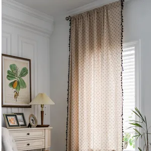 Detail of linen curtains featuring black polka dots and decorative tassel fringe edges