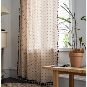 Detail of beige cotton linen curtain with black floral pattern and tassel fringe trim