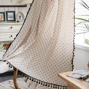Close-up of cotton linen curtain with floral pattern and black tassel trim detail