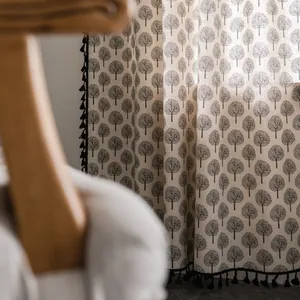 Detail of beige cotton linen curtain featuring black tree prints and tassel fringe decor