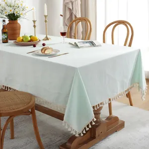 Détail de la nappe en lin vert menthe avec bordures de pompons blancs et texture tissée
