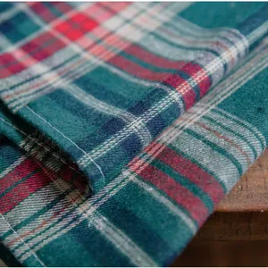 Detail of red and green plaid fabric showing cotton texture and precise white stitching