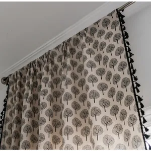 Detail of linen curtain with tree patterns, black tassels, and rod pocket header style