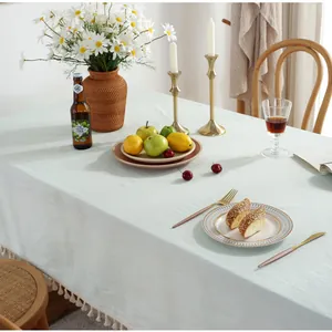 Détail de la nappe en lin vert sauge avec finitions pompons ivoire au style nordique