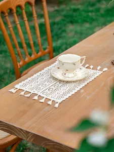 Détail du motif floral au crochet et des glands sur le chemin de table en dentelle