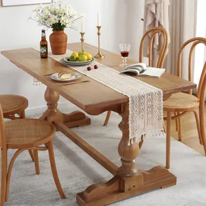 Chemin de table en dentelle blanche crochetée avec motifs floraux et pompons sur table bois