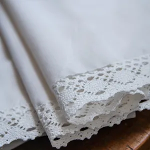 Cortina de lino blanco con borde de encaje calado elegante sobre fondo de madera oscura