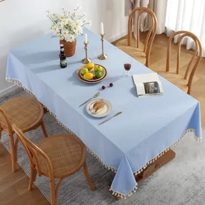 Détail de la nappe en coton bleu clair avec texture flammée et pompons blancs