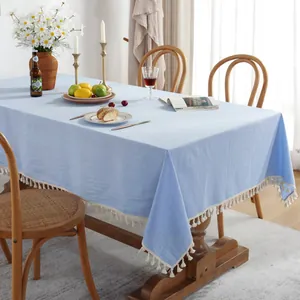 Détail de la nappe bleu clair en coton et lin ornée de pompons blancs décoratifs