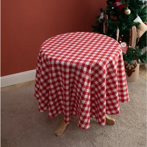 Detailed view of a round red and white checkered tablecloth on a wooden table for Christmas
