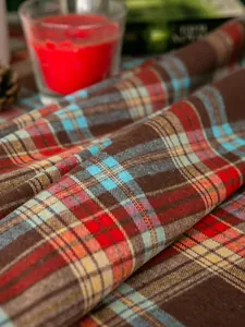 Makroaufnahme einer rot karierten Baumwoll-Leinen-Tischdecke mit winterlicher Deko