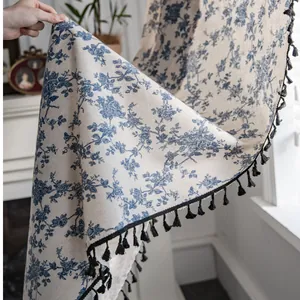 Detail of vintage blue floral linen curtain with black pom-pom trim and elegant drape