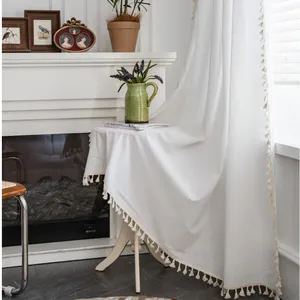 Dettaglio tenda in lino bianco con eleganti nappe color crema lungo il bordo