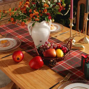 Detail of red and brown plaid table runner with festive Christmas decor on wooden table
