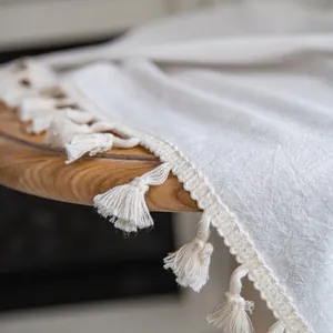 Dettaglio di tessuto in cotone e lino bianco crema con decorazione di frange nappe