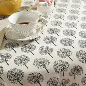 Close-up of linen tablecloth with black tree prints and cozy tea set setting