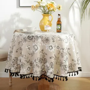 Detail of round floral tablecloth with black tassels and elegant vintage flower print