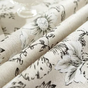 Macro texture of linen fabric showing black floral daisy pattern and fringe details