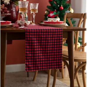 Detailed view of red and black buffalo plaid Christmas table runner on wooden table