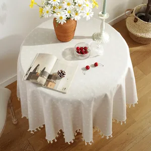 Detail of round linen tablecloth featuring vintage floral patterns and fringe tassels