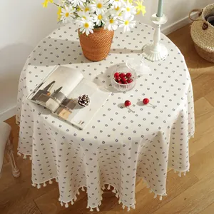 Detail of round cotton linen tablecloth with blue floral patterns and tassel edges
