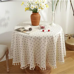 Detail of vintage round tablecloth with floral pattern and white cotton tassels