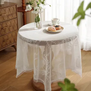 Detail of white lace tablecloth with intricate crochet floral patterns and wavy edges