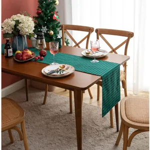 Detail of green and black plaid cotton linen table runner on a wooden dining table