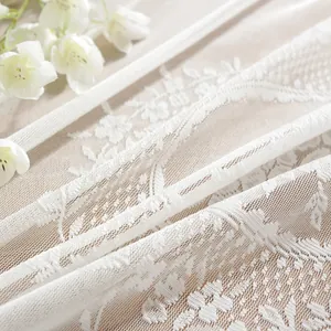 Detailed macro view of white lace tablecloth with floral embroidery and ruffled mesh edge