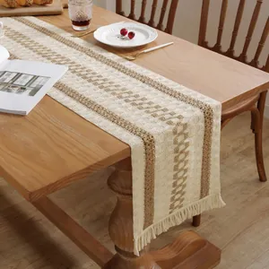 Detail of bohemian cotton linen table runner with brown geometric patterns and fringe