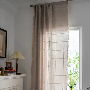 Detailed close-up of farmhouse plaid curtain fabric with delicate white fringe tassels