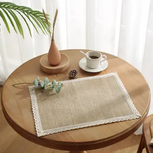 Makroaufnahme eines rechteckigen Jute-Platzsets mit zarter weißer Spitze auf einem Holztisch