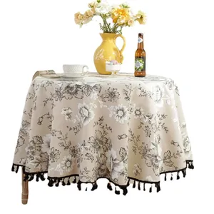 European vintage floral round tablecloth with black tassels on a wooden table