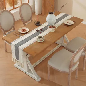 Detail van een natuurlijke tafelloper met grijze strepen en kwastjes op een houten tafel