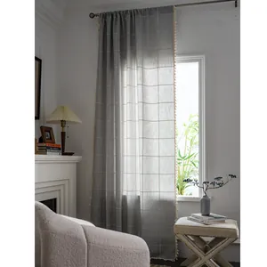 Grey grid farmhouse curtain with elegant tassel edges in a warm home interior setting