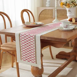 Detail of red geometric diamond pattern on linen table runner with woven borders