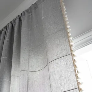 Detail view of grey plaid farmhouse curtain with white grid pattern and decorative tassels